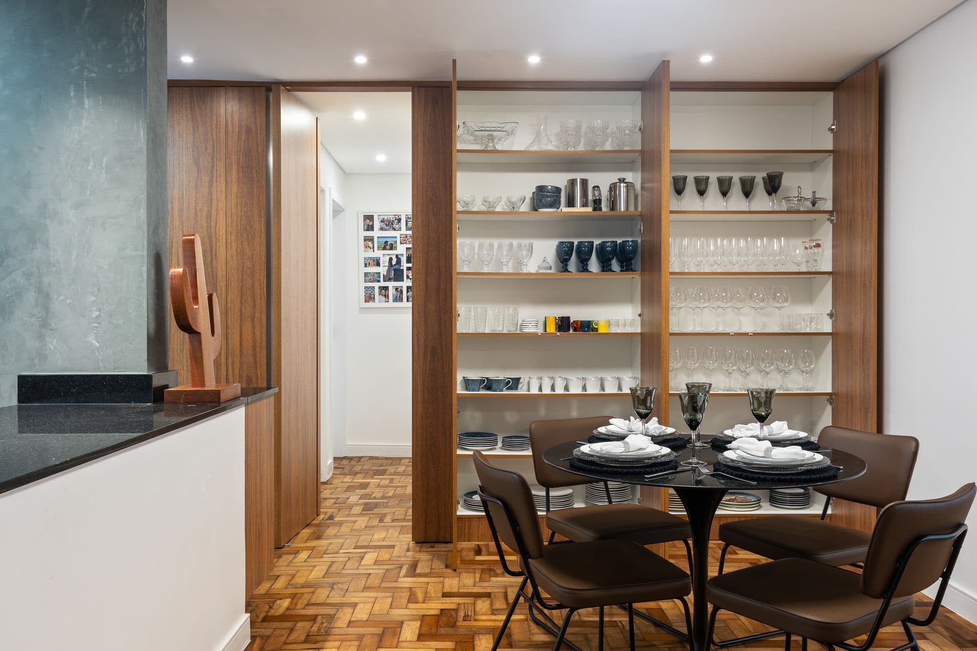 Sala de jantar com o painel de madeira aberto, revelando a cristaleira