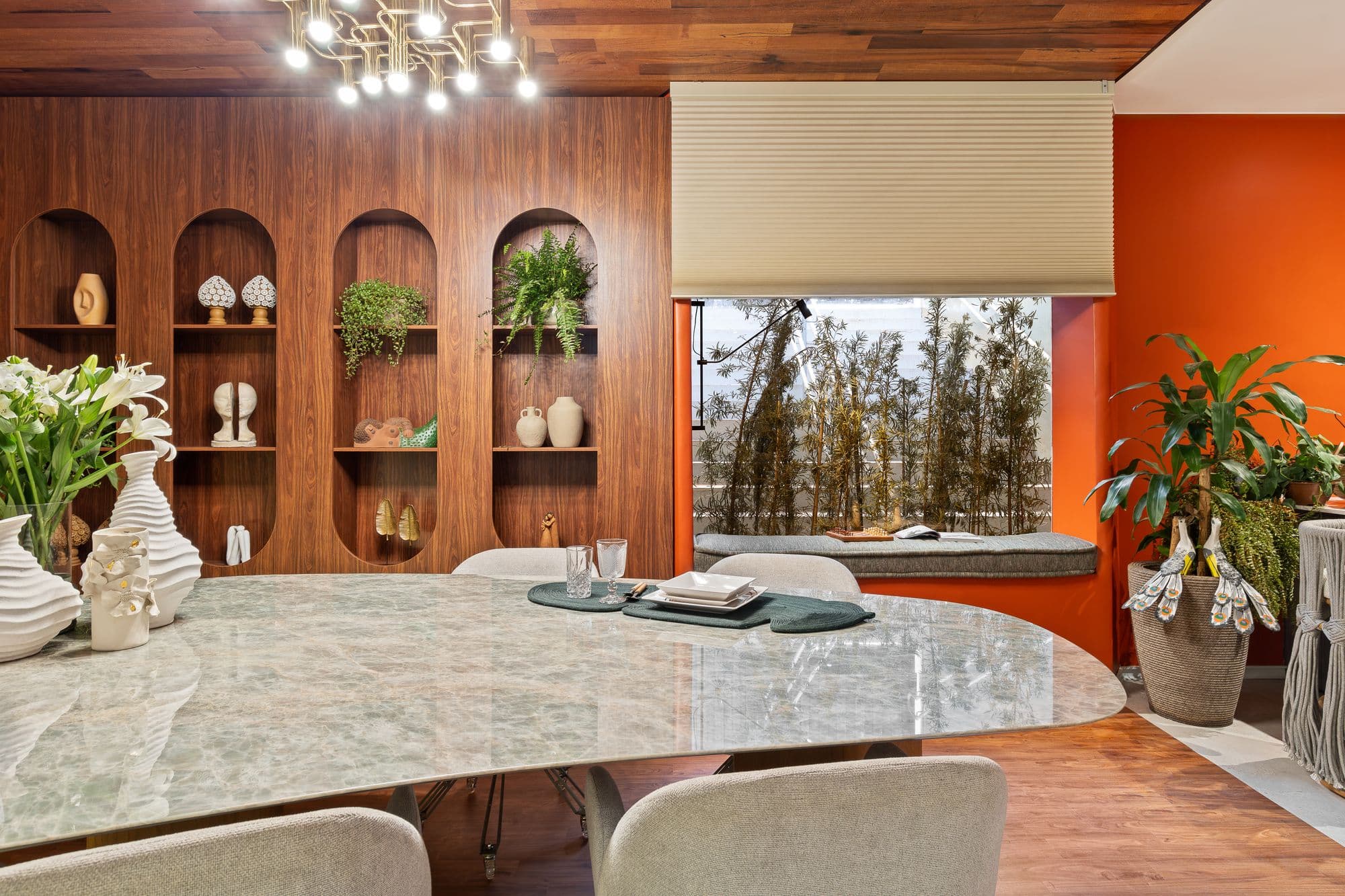 Sala de jantar com estante de nichos em arco, mesa orgânica e parede laranja