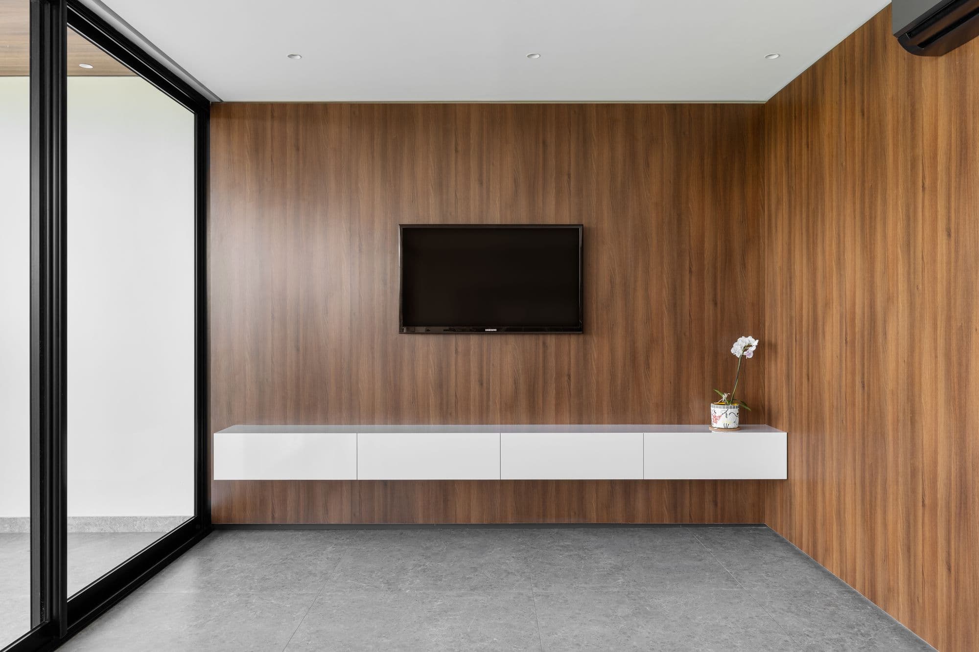 Sala com painel de madeira, TV e rack branco suspenso